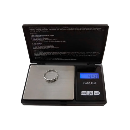 Báscula digital de bolsillo negra 500g de precisión. Plataforma plateada pesando anillo, display muestra 4.50g.