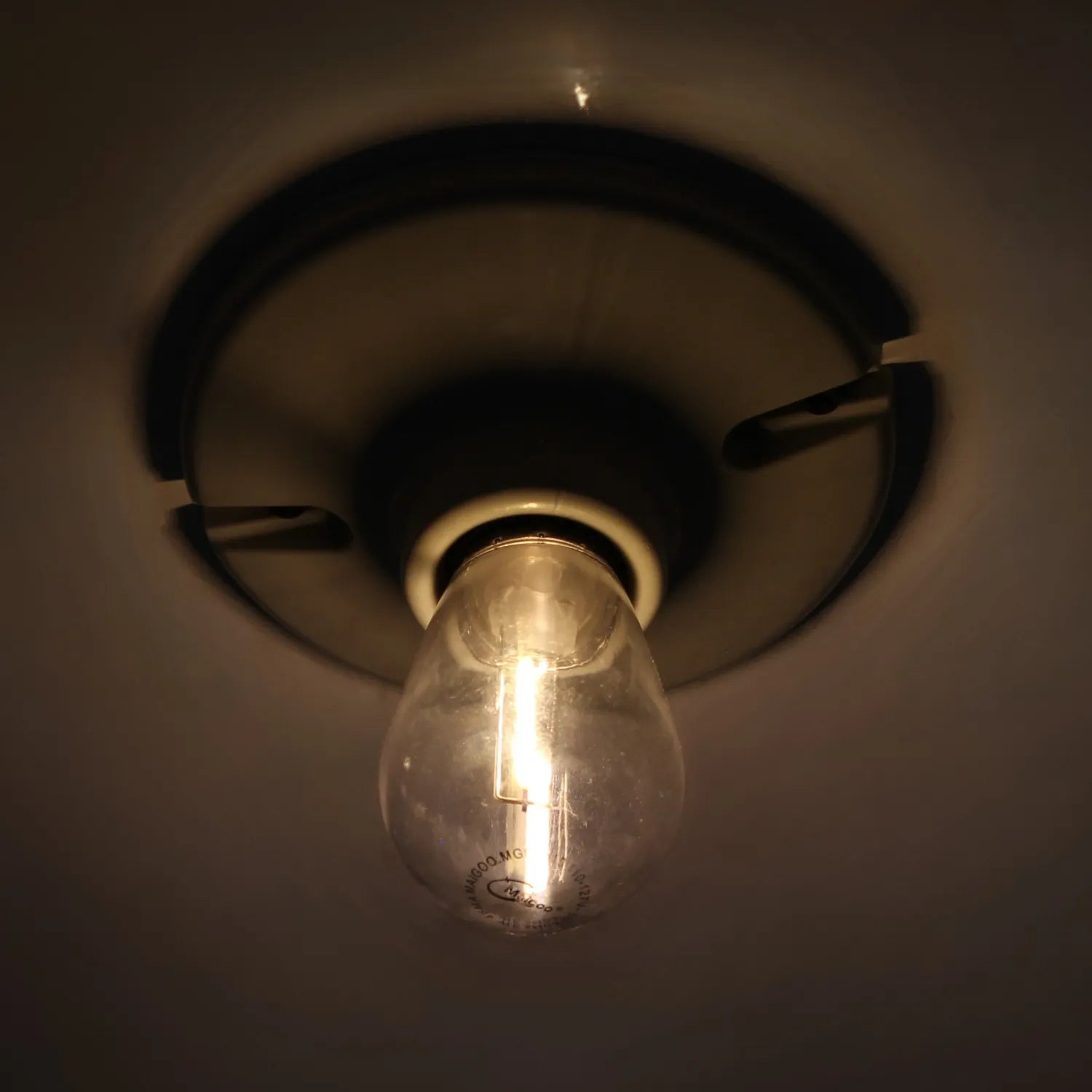 Bombilla de filamento transparente 127V encendida en base de techo para iluminación cálida de interiores
