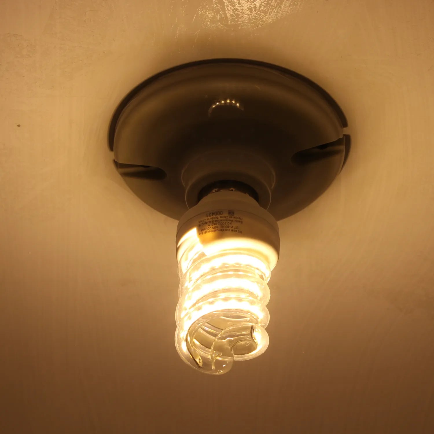 Foco espiral ahorrador de 14W luz cálida instalado en plafón de techo para iluminación de interiores.